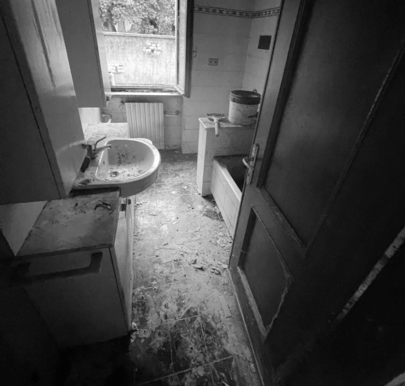 Prima della pulizia: bagno con pavimento sporco, lavabo e vasca