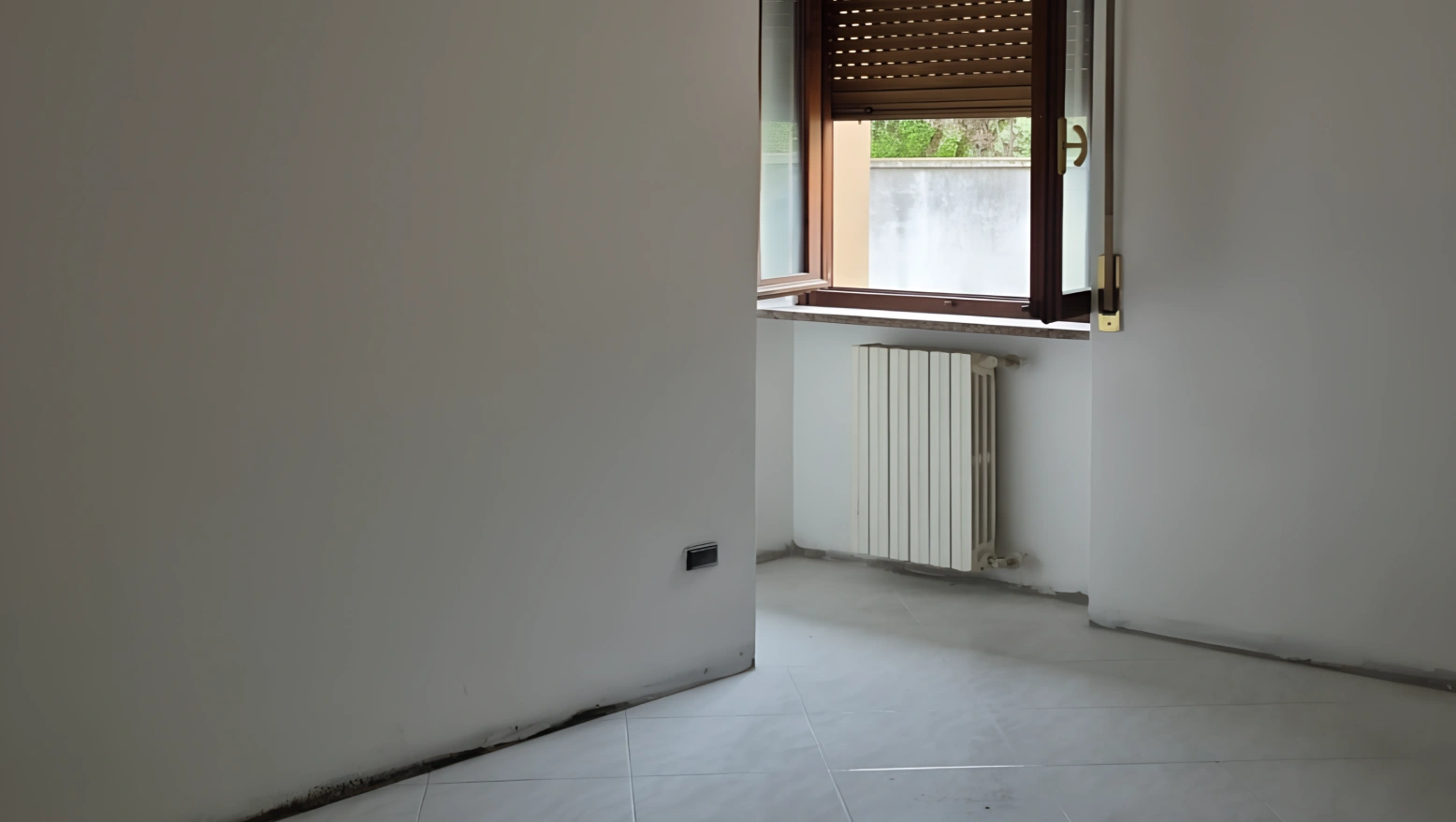 Stanza vuota con finestra e radiatore dopo sgombero e sanificazione a ozono