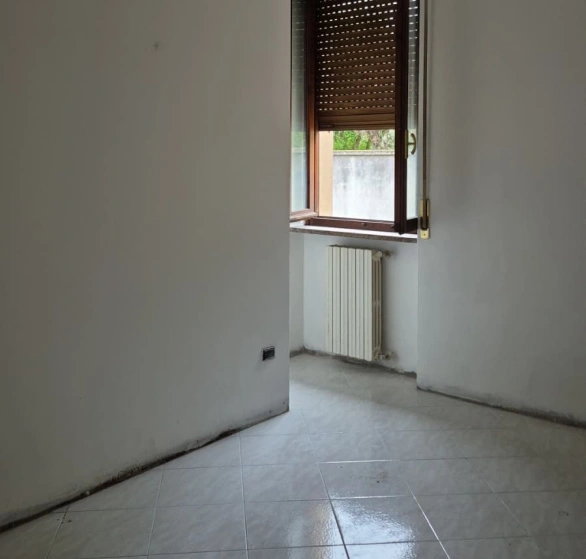 Dopo sgombero, sanificazione e tinteggiatura: stanza vuota con finestra e radiatore
